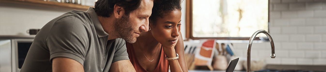 Couple having financial planning in a kitchen with documents for budget, savings and paying bills.