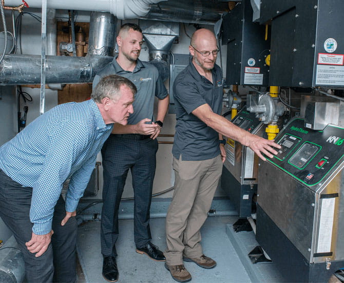 A group of men standing next to a machine.