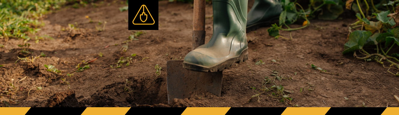 A person wearing boots and standing on a shovel